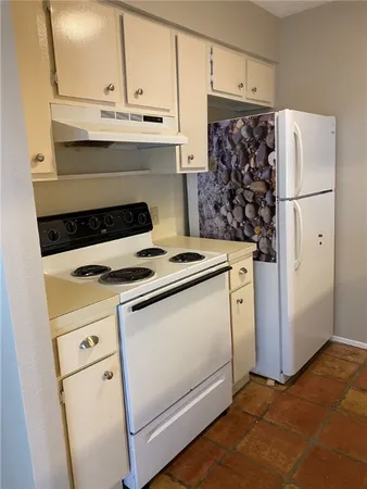 a white refrigerator freezer and a stove sitting inside of a kitchen