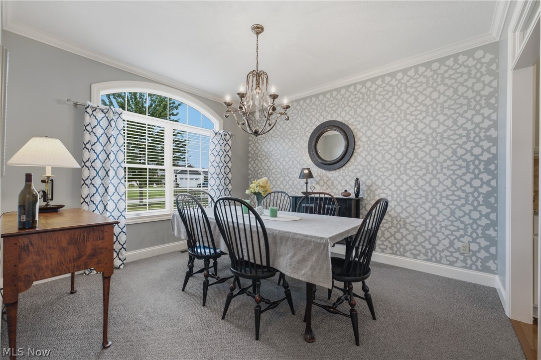 3955 Spring Brook Way Wooster, OH 44691 - Photo 8 of 50 Arched transom window with blinds, carpeted flooring, wall with patterned finish, crown molding, and an ornate chandelier