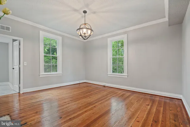 an empty room with wooden floor fireplace and windows