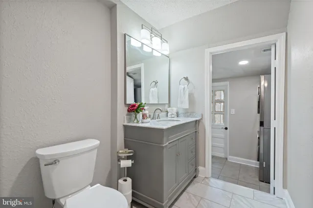 a bathroom with a granite countertop sink a toilet a large mirror and a window