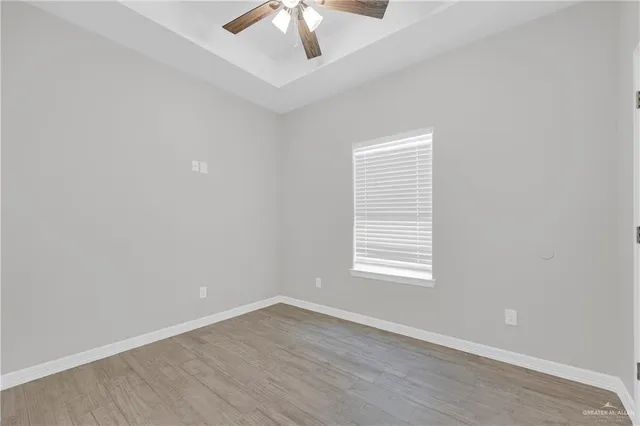an empty room with wooden floor chandelier fan and windows