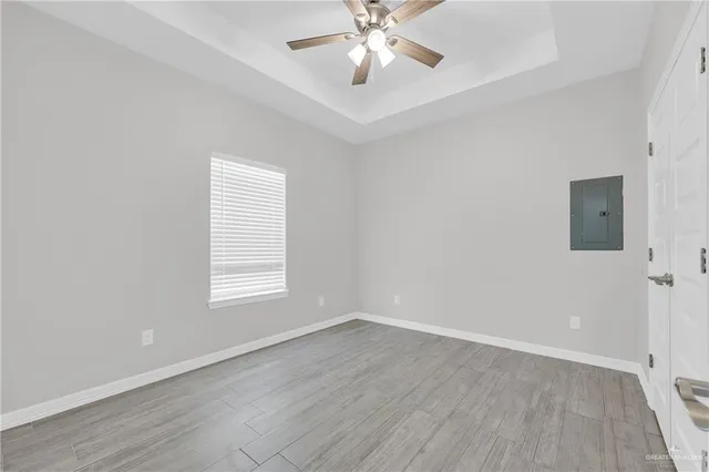 an empty room with wooden floor and ceiling fan