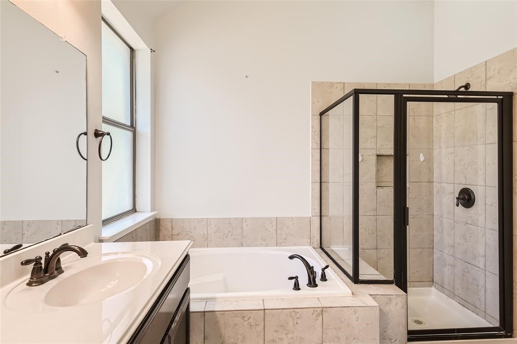 290 Maeves Way Austin, TX 78737 - Photo 9 of 13 Indulge in a serene primary bath featuring a deep soaking tub and a sleek glass-enclosed shower.