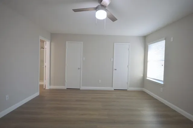 an empty room with wooden floor closet and windows