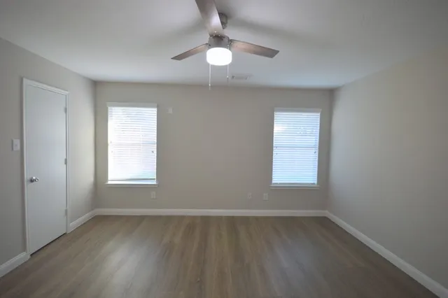 an empty room with wooden floor and windows