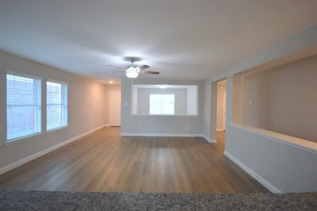 a view of an empty room with wooden floor and a window
