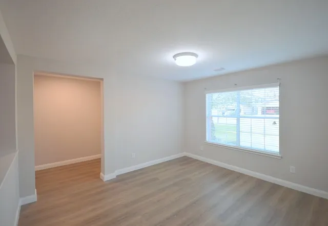 an empty room with wooden floor and windows