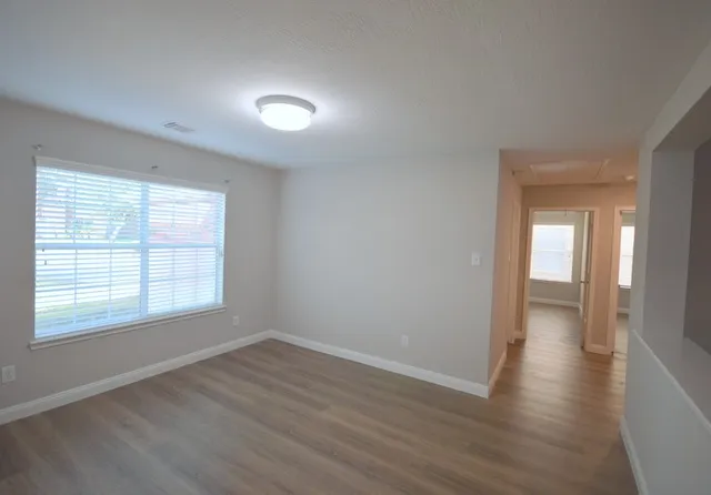 a view of an empty room with wooden floor and a window