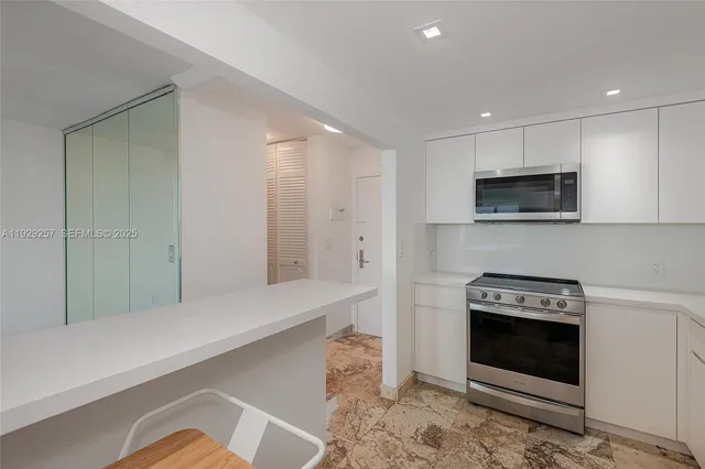 a kitchen with stainless steel appliances a stove a microwave and white cabinets