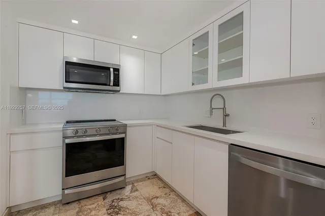 a kitchen with stainless steel appliances a stove microwave and sink