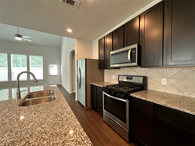 a kitchen with stainless steel appliances granite countertop a stove a sink and a microwave