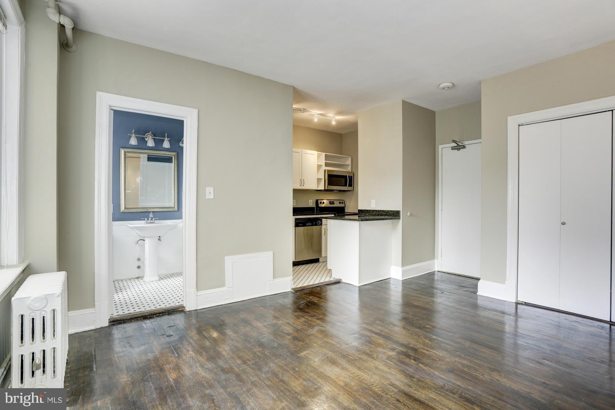 1954 Columbia Road Northwest, Unit 408 Washington, DC 20009 - Photo 5 of 12 a view of a kitchen with an empty space and wooden floor