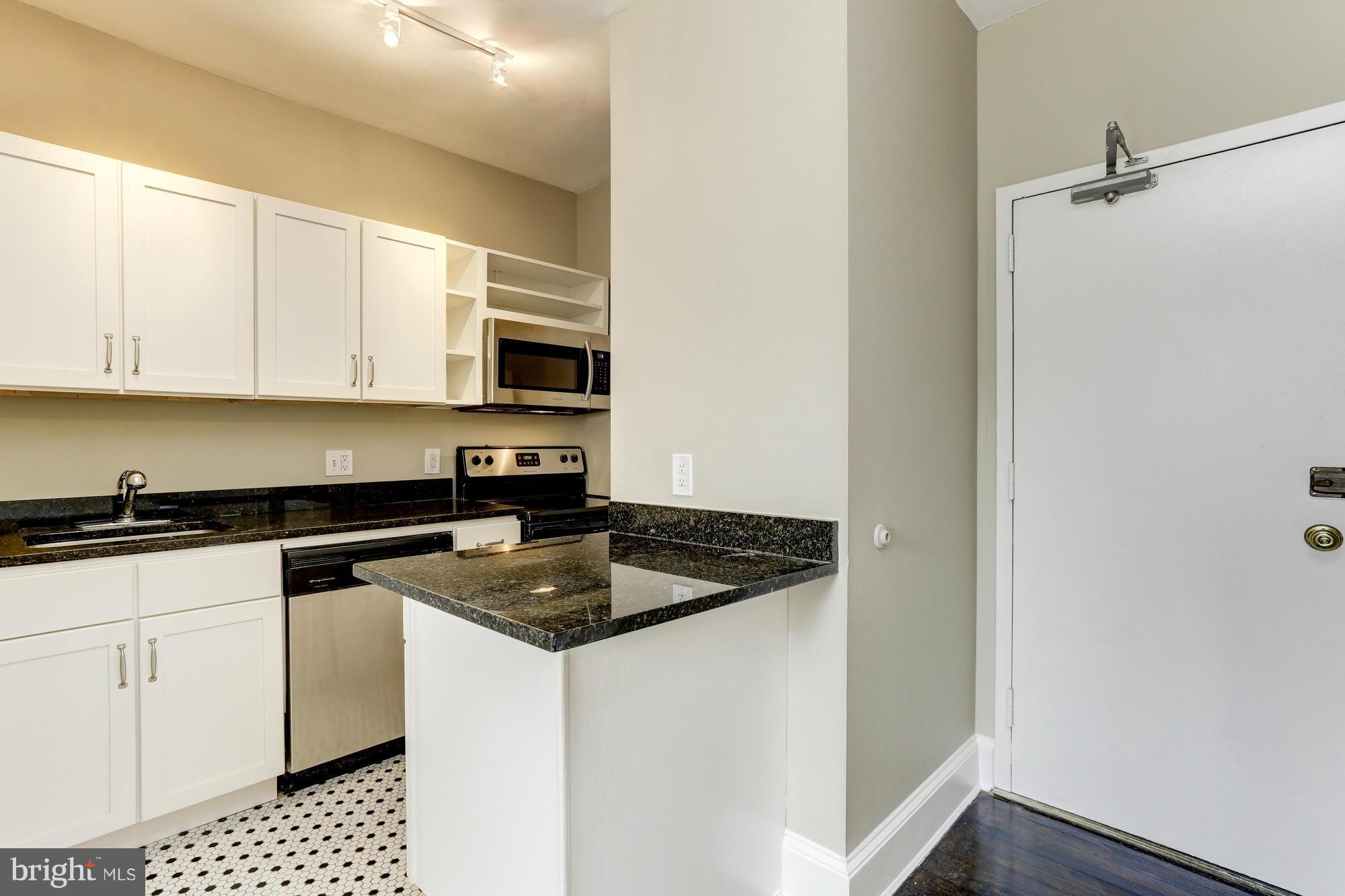 1954 Columbia Road Northwest, Unit 408 Washington, DC 20009 - Photo 7 of 12 a kitchen with granite countertop white cabinets and black appliances