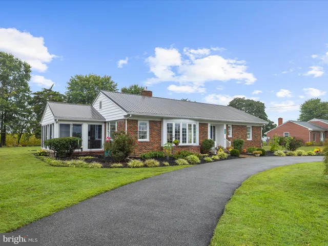 a front view of a house with a garden and trees