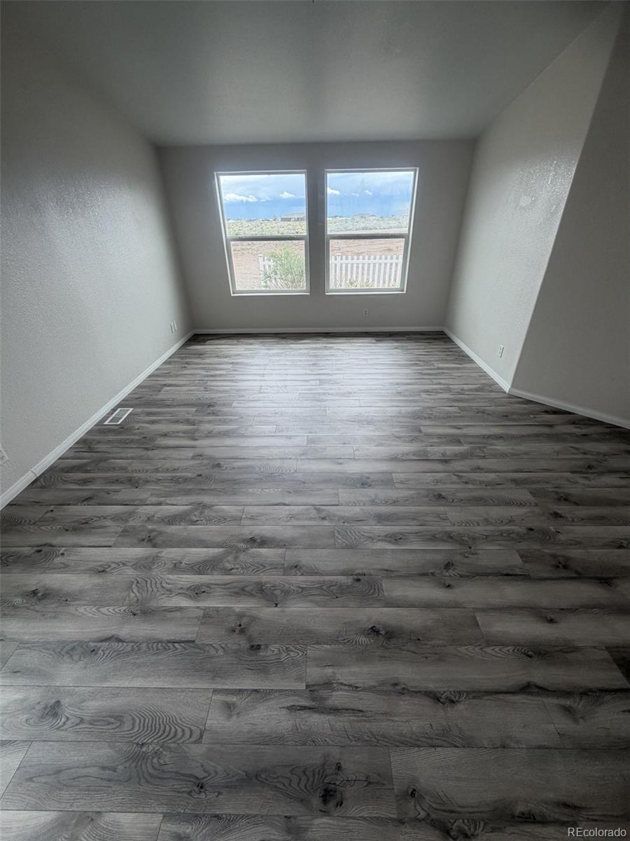 5511 Ridgetop Court Alamosa, CO 81101 - Photo 5 of 10 wooden floor in an empty room with a window
