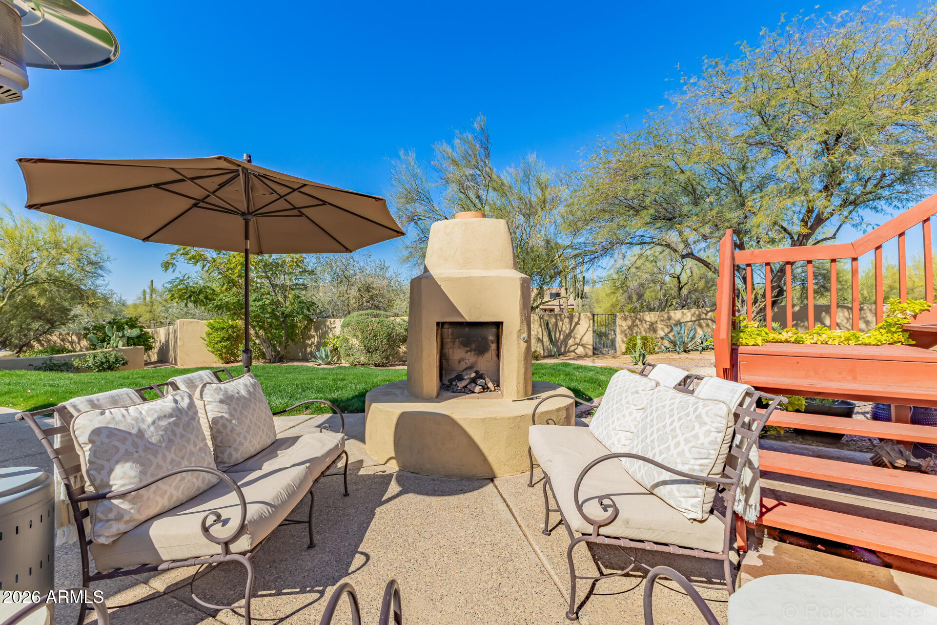 8549 East Bronco Trail Scottsdale, AZ 85255 - Photo 58 of 67 a view of a patio with couches table and chairs under an umbrella with a fire pit