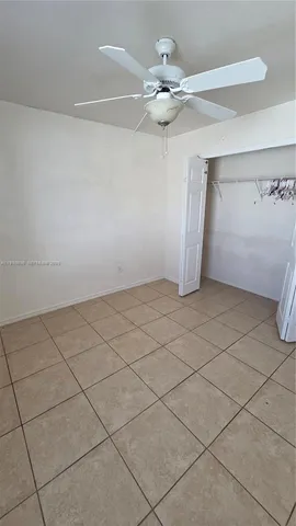 a view of an empty room and chandelier fan
