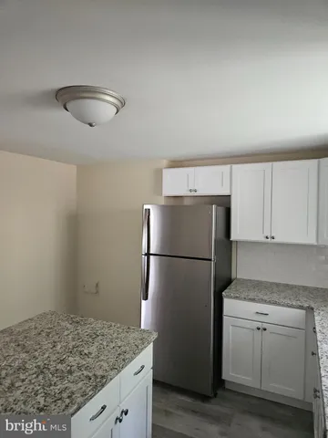 a kitchen with a sink a refrigerator and white cabinets