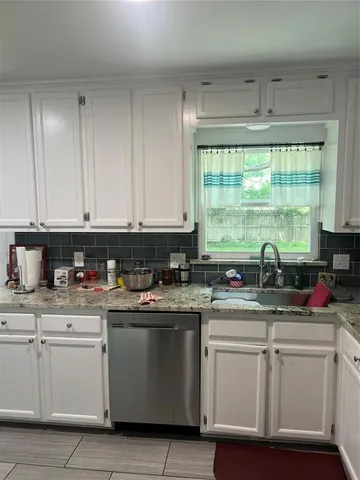 a kitchen with white cabinets appliances and a window