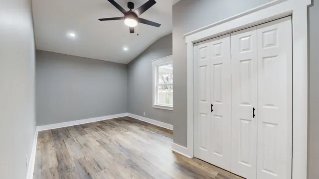 an empty room with wooden floor cabinet and windows