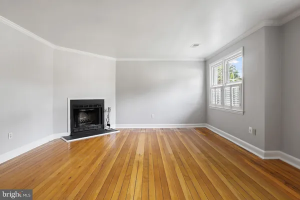 a view of empty room with wooden floor and fireplace