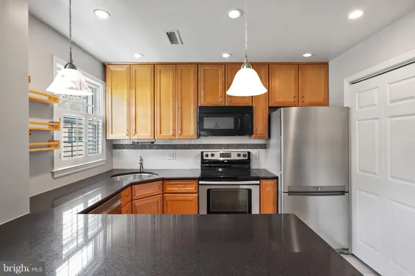 a kitchen with a refrigerator a microwave oven a sink and a dining table with wooden floor