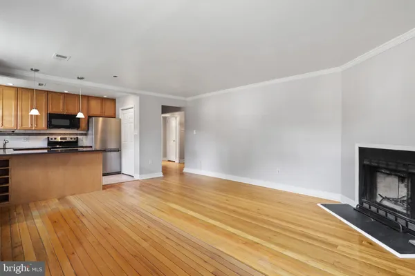 a view of kitchen and empty room with wooden floor