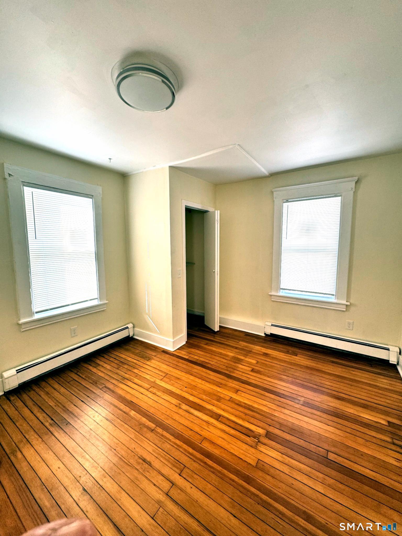 175 Wilson Street, Unit 179 Bridgeport, CT 06605 - Photo 8 of 9 an empty room with wooden floor and windows