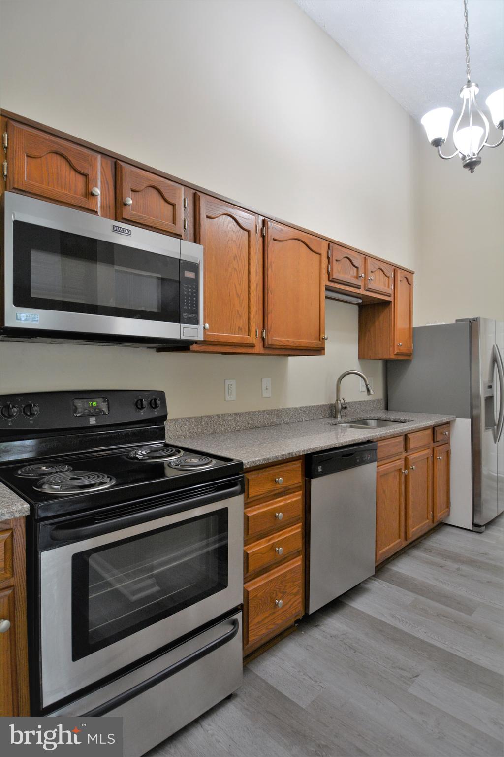 1307 J Clover Valley Way, Unit 1307J Edgewood, MD 21040 - Photo 10 of 25 a kitchen with stainless steel appliances a stove a microwave cabinets and a wooden floor