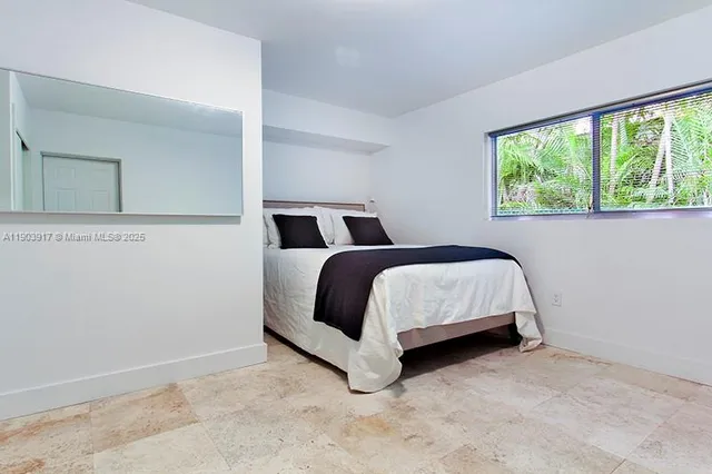 a bed sitting in a bedroom next to a window