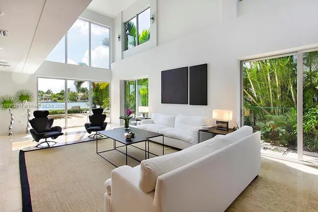 a living room with patio furniture and floor to ceiling windows