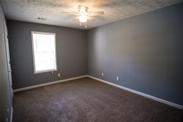 an empty room with a chandelier fan and windows