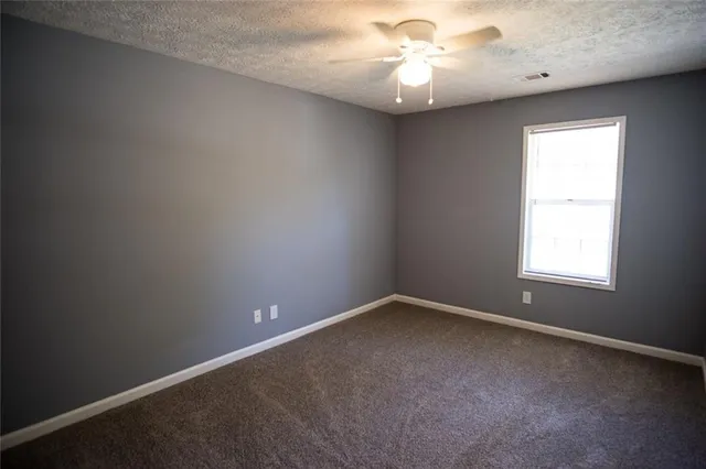 an empty room with a window and a fan