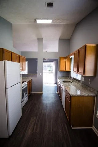 a kitchen with granite countertop a sink a counter top space stainless steel appliances and cabinets