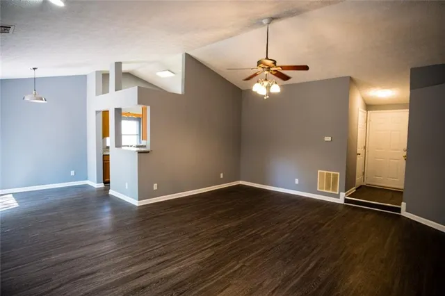 a view of an empty room with window and wooden floor