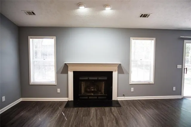 an empty room with wooden floor fireplace and windows