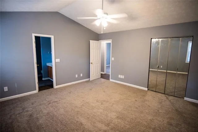 an empty room with closet and a ceiling fan