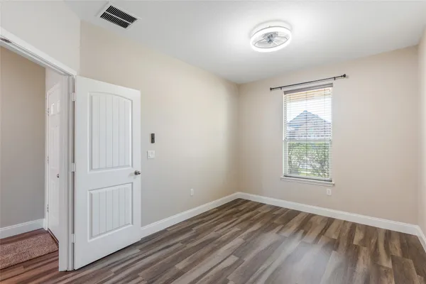 a view of empty room with wooden floor and fan