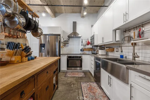 a kitchen with stainless steel appliances granite countertop a sink and dishwasher a refrigerator a stove top oven with wooden floor