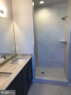 a bathroom with a granite countertop sink a shower and a mirror