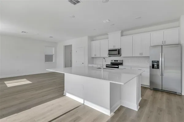 a kitchen with granite countertop a refrigerator stove top oven and sink