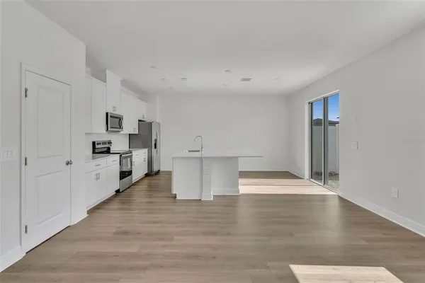 a view of kitchen and empty room with wooden floor