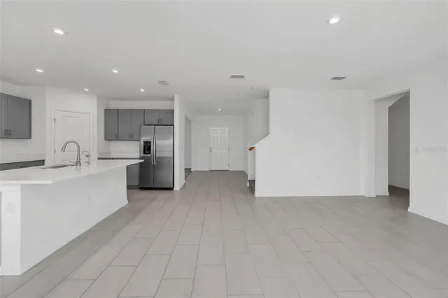 a large white kitchen with a refrigerator a sink and a stove top oven