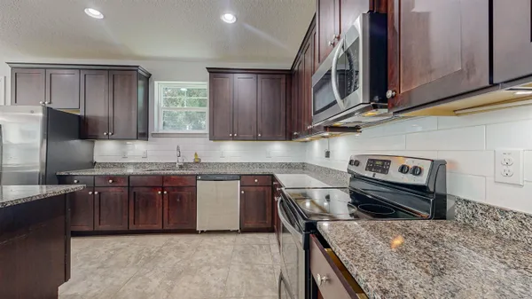a kitchen with granite countertop wood cabinets stainless steel appliances and a sink