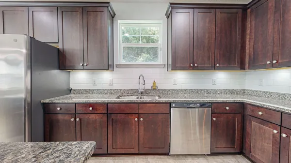 a kitchen with granite countertop a refrigerator and a sink