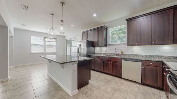 a kitchen with stainless steel appliances kitchen island granite countertop a refrigerator a sink a stove and a refrigerator