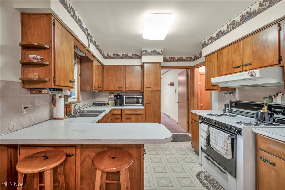 3524 Oak Road Stow, OH 44224 - Photo 5 of 19 Kitchen featuring white range oven, under cabinet range hood, light countertops, a peninsula, and light flooring