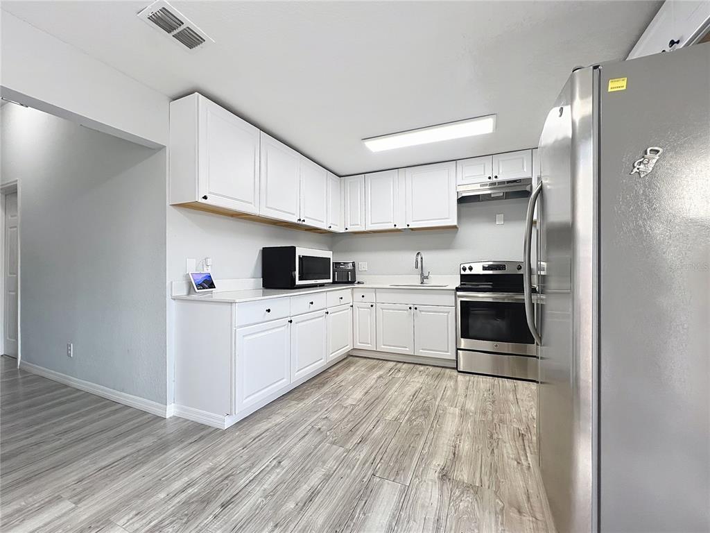 1109 5th Street Southwest Winter Haven, FL 33880 - Photo 10 of 20 a kitchen with white cabinets and stainless steel appliances