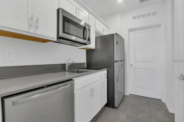 a kitchen with stainless steel appliances granite countertop white cabinets and a refrigerator