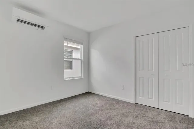 a view of an empty room with closet and a window